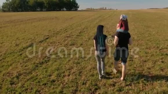 家庭休息日妈妈爸爸和女儿走在无尽的田野上美丽的夏日风景后景视频的预览图
