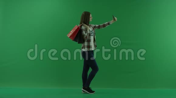 女孩的肩膀上有购物袋站在她的右边在绿色屏幕上自拍视频的预览图