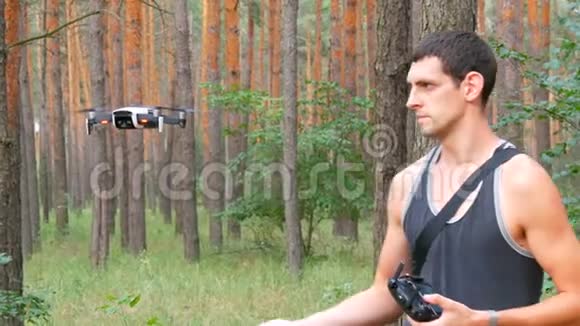 一个可爱的高个子男人在树林里发射并持有一架无人机或四架直升机视频的预览图