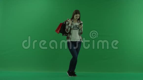 女孩站在半个转弯处看着右边肩膀上放着袋子在手机上写着绿色的东西视频的预览图