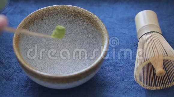 在蓝色表面的碗里准备绿茶抹茶的人视频的预览图