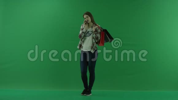 女孩站在一个半转弯处看着左边肩膀上放着袋子在绿色屏幕上通过电话交谈视频的预览图