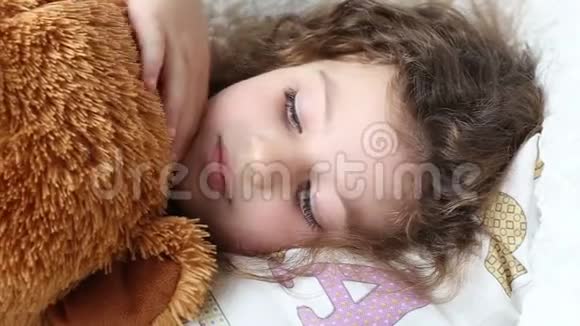 一个小女孩拿着一只玩具熊躺在沙发上特写镜头追踪镜头视频的预览图