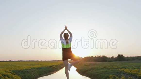 一个有目的的女人单腿站立并做瑜伽练习那女孩在日落时从事体育运动视频的预览图