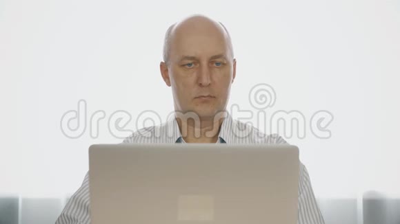 戴眼镜的严肃男人用笔记本电脑和杯子喝茶视频的预览图