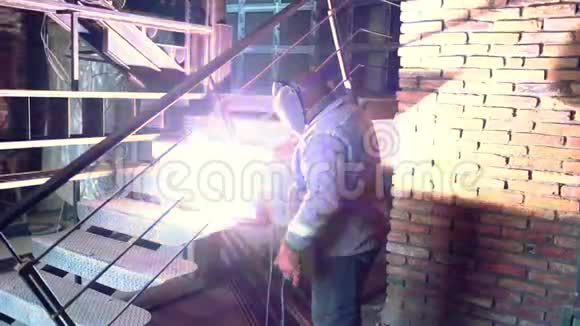 金属焊接男焊工在铁楼梯上戴防护面罩作业工业建设理念来自视频的预览图