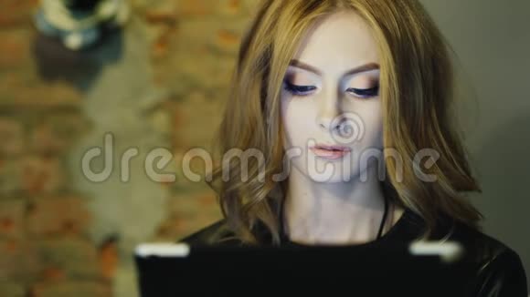 年轻漂亮的女人在平板电脑上看新闻视频的预览图