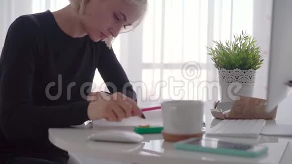 侧视年轻的商务女性坐在桌子旁在笔记本上做笔记博客视频的预览图