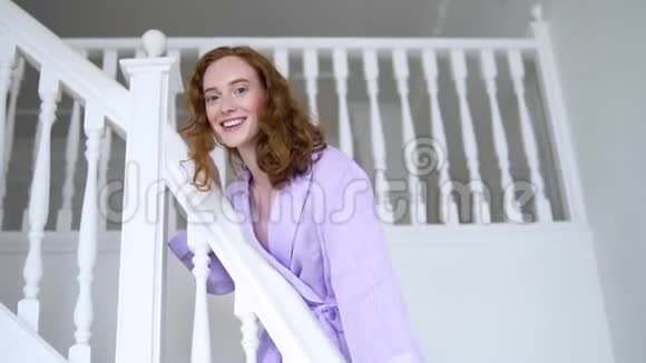穿着紫色西装站在白色梯子上为相机摆姿势的开朗积极的女孩视频的预览图