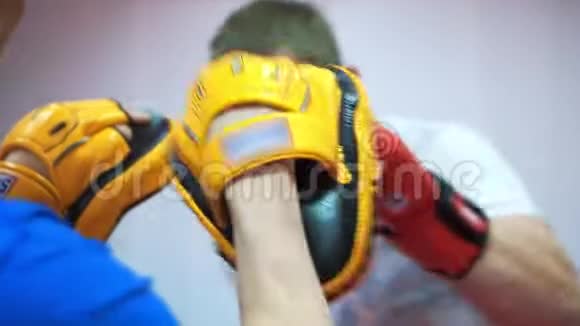 在拳击馆训练一名中年运动员和他的教练戴着拳击手套罢工视频的预览图