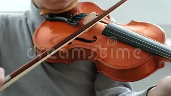 拉小提琴无法辨认的七岁男孩在拉小提琴特写前景视频的预览图