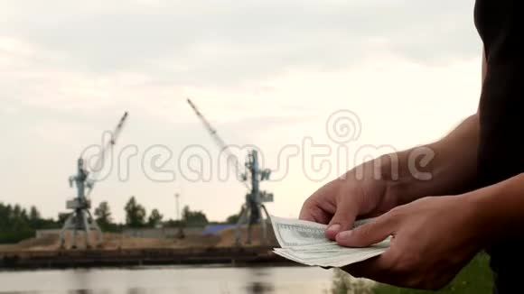 在港口生产河沙的货物起重机的背景下一个人计算金钱收据视频的预览图