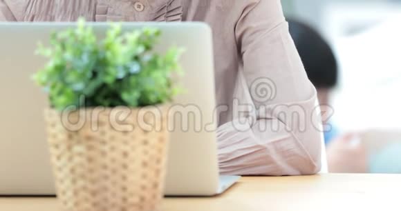 一个有魅力的成熟的女商人在家里的工作站上用笔记本电脑工作而男孩玩平板电脑视频的预览图