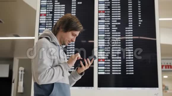 旅行者在机场使用智能手机年轻的白种人旅行者用手机应用程序检查登机时间视频的预览图