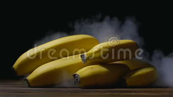 一堆卡文迪什香蕉在桌子上烟从后面慢慢地吹过来关上了视频的预览图