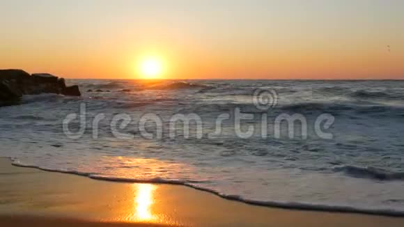 日出或非常美丽的日落在海滨沙滩和海浪拍打着海滩泡沫大风暴波视频的预览图