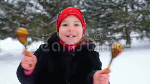 一个穿着毛皮大衣戴着俄罗斯风格的红领巾的小女孩在木勺上玩耍视频的预览图