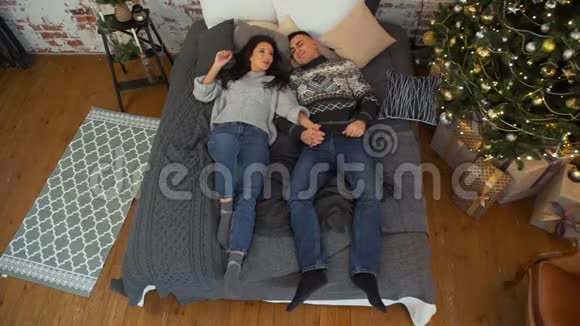 一对夫妇躺在圣诞树附近视频的预览图