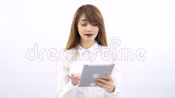 带刘海的金发美女使用白色背景的平板电脑视频的预览图