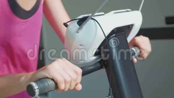 运动缓慢的年轻女子在健身馆骑自行车的画像视频的预览图