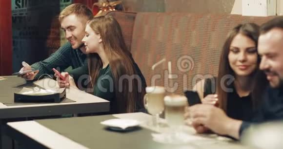 两对年轻夫妇坐在一张桌子旁的咖啡馆里视频的预览图