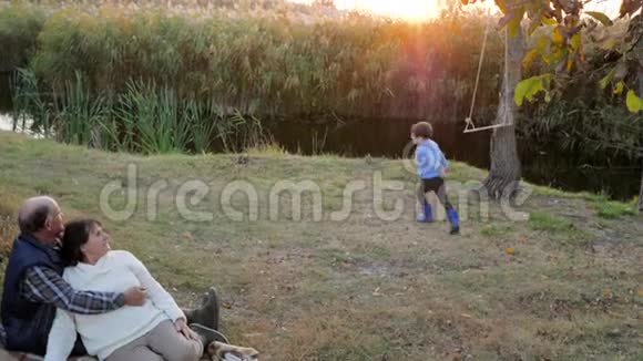 年长夫妇和他们的孙子在户外玩背景是日落时的秋色自然视频的预览图