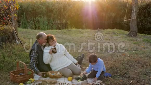 家庭关系有孙子的老人在日落河边野餐视频的预览图