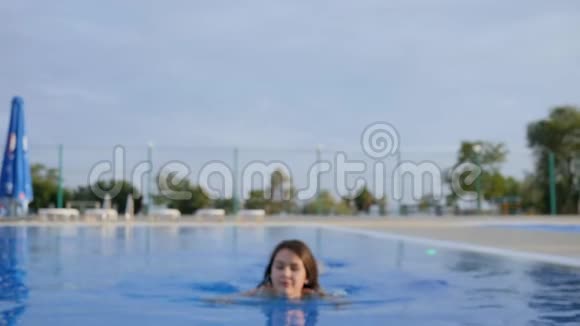 女孩在暑假的背景天空的池边喝着五颜六色的鸡尾酒竖起大拇指视频的预览图
