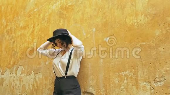 一个戴帽子的女孩站在墙边环顾四周视频的预览图