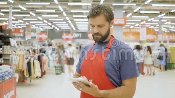 超级市场的帅哥店员在超市里用触摸屏平板电脑视频的预览图