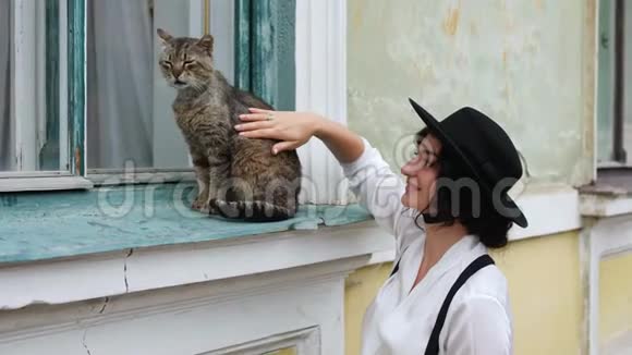 一个戴帽子的女孩用手抚摸一只猫视频的预览图