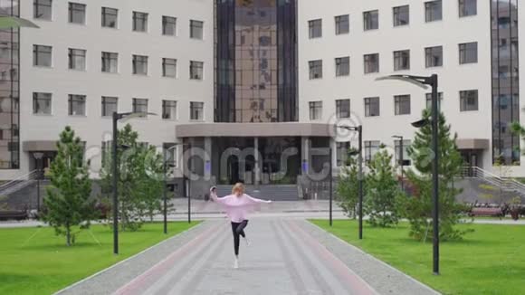 大学背景下的年轻女子手里拿着手机跳着舞穿粉色衣服的女生视频的预览图