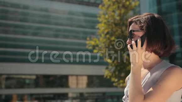 商务年轻女性深色头发拿着智能手机说话态度积极视频的预览图