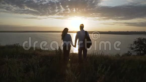 情侣欣赏夕阳漫步河岸视频的预览图