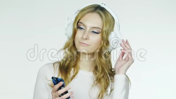 迷人的女人在耳机上听浪漫的音乐白色背景视频视频的预览图