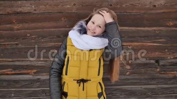 穿着冬装的年轻漂亮女孩正对着镜头在一座木屋的背景上摆姿势视频的预览图