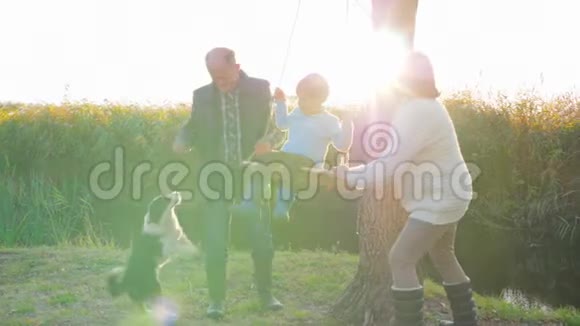 在阳光照耀下的小湖上一对年长夫妇和可爱的孩子在大自然中愉快的旅行视频的预览图
