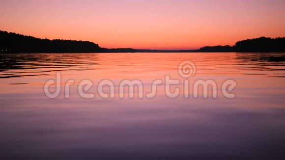 令人惊叹的彩色粉红色日落天空和湖面平静的自然4K背景录像视频的预览图