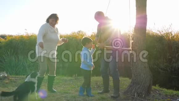 爷爷在树上荡秋千小男孩和奶奶在阳光下玩家庭宠物视频的预览图