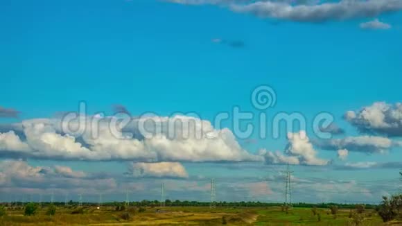 草原高压电力线路在时间推移模式下快速移动的云高压塔天空背景视频的预览图