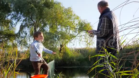秋天的休息鲫鱼在钓竿上交到爷爷手中和男孩在水道上的大自然视频的预览图