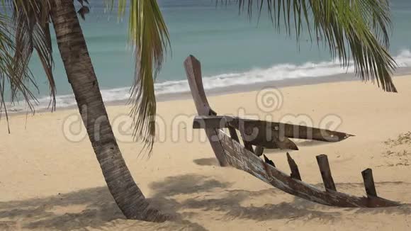 在椰树下的异国海滩上废弃的木船视频的预览图