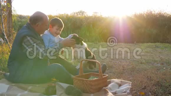 快乐的童年孙子和爷爷狗在春天野餐时在大自然中休息视频的预览图