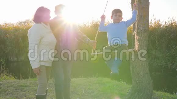 有孩子在秋千上的配偶祖父母周末在大自然中玩得很开心视频的预览图