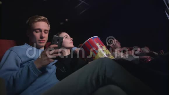 在电影院里用智能手机的年轻人在电影院打电话的年轻人视频的预览图