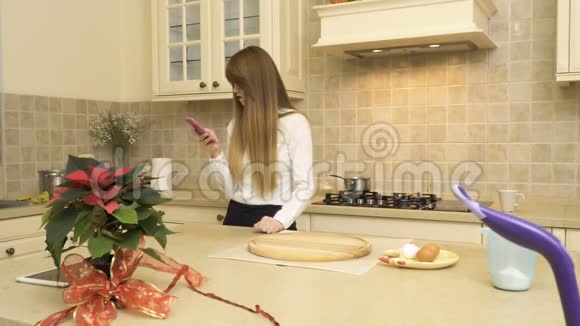 漂亮女孩在厨房用电话视频的预览图