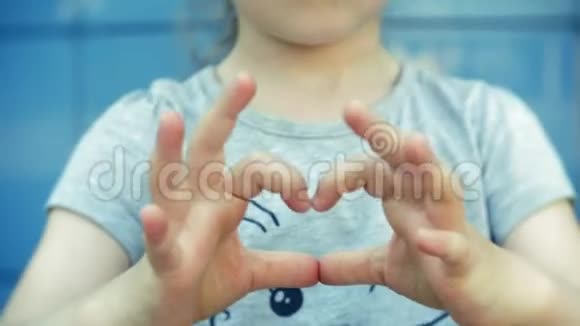 小女孩用手在心脏上做手势视频的预览图