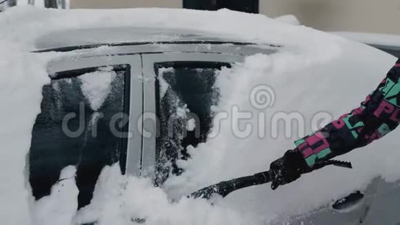 用刷子把她的车从冬天的雪中擦干净视频的预览图