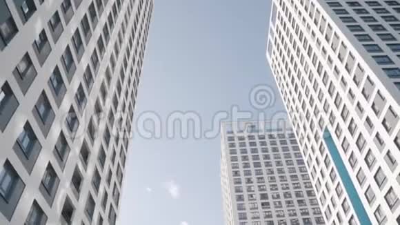 白色摩天大楼对蓝天的角度视图框架在我们的视野下视频的预览图