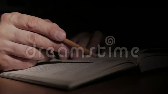 一个人的手一本打开的纸书用铅笔在纸上写一张纸条视频的预览图